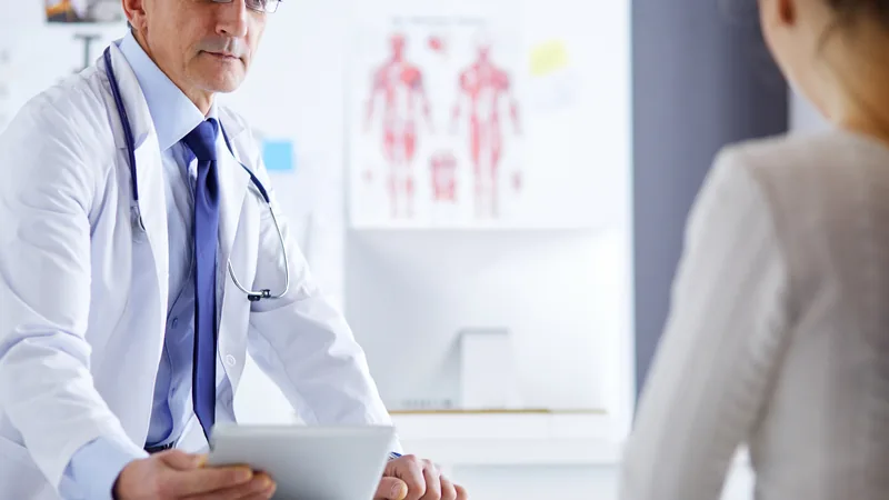 Urologista PJ analisando documentos financeiros em seu consultório, com gráficos e calculadora ao fundo, simbolizando a gestão contábil.