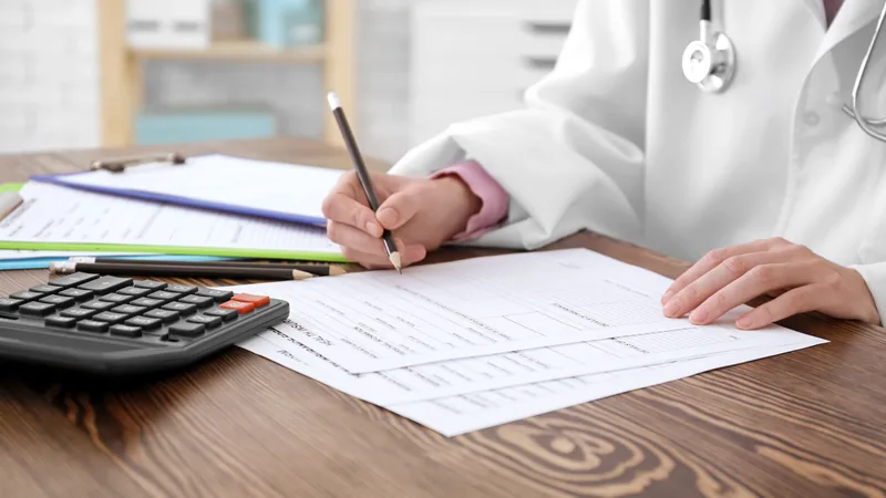 Médico PJ analisando um DARF DAS em seu computador, com calculadora e documentos fiscais ao lado, simbolizando a gestão tributária eficiente.