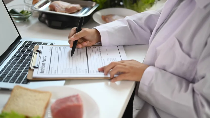 Nutricionista PJ analisando documentos fiscais e gráficos de IRPF em um tablet, com símbolos de dinheiro e impostos ao fundo, representando a gestão tributária.