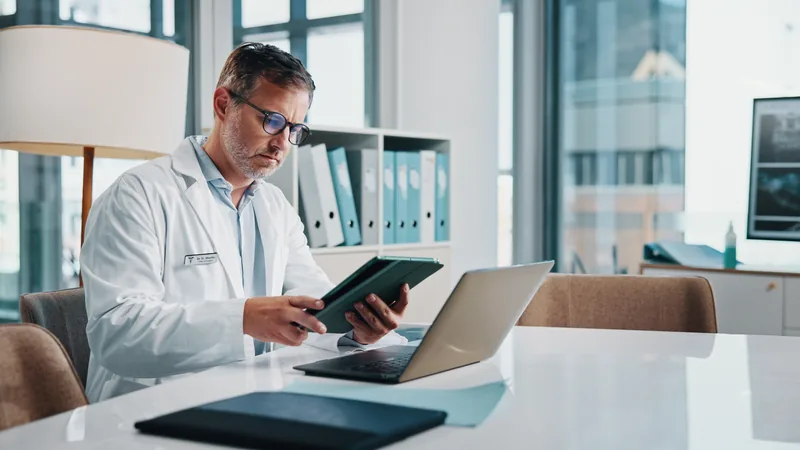 Médico PJ analisando documentos financeiros, simbolizando a complexidade e a importância do Lucro Real para especialistas da saúde.